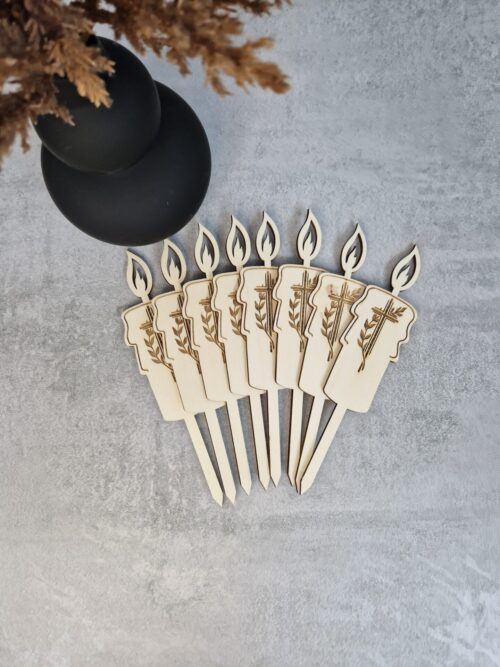 Lesene sveče s križem in vejico za cvetlične aranžmaje, zapičene v zemljo.