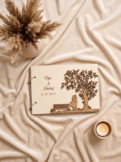 Personaliziran lesen poročni album z vgraviranimi imeni in datumom na ozadju zavese.